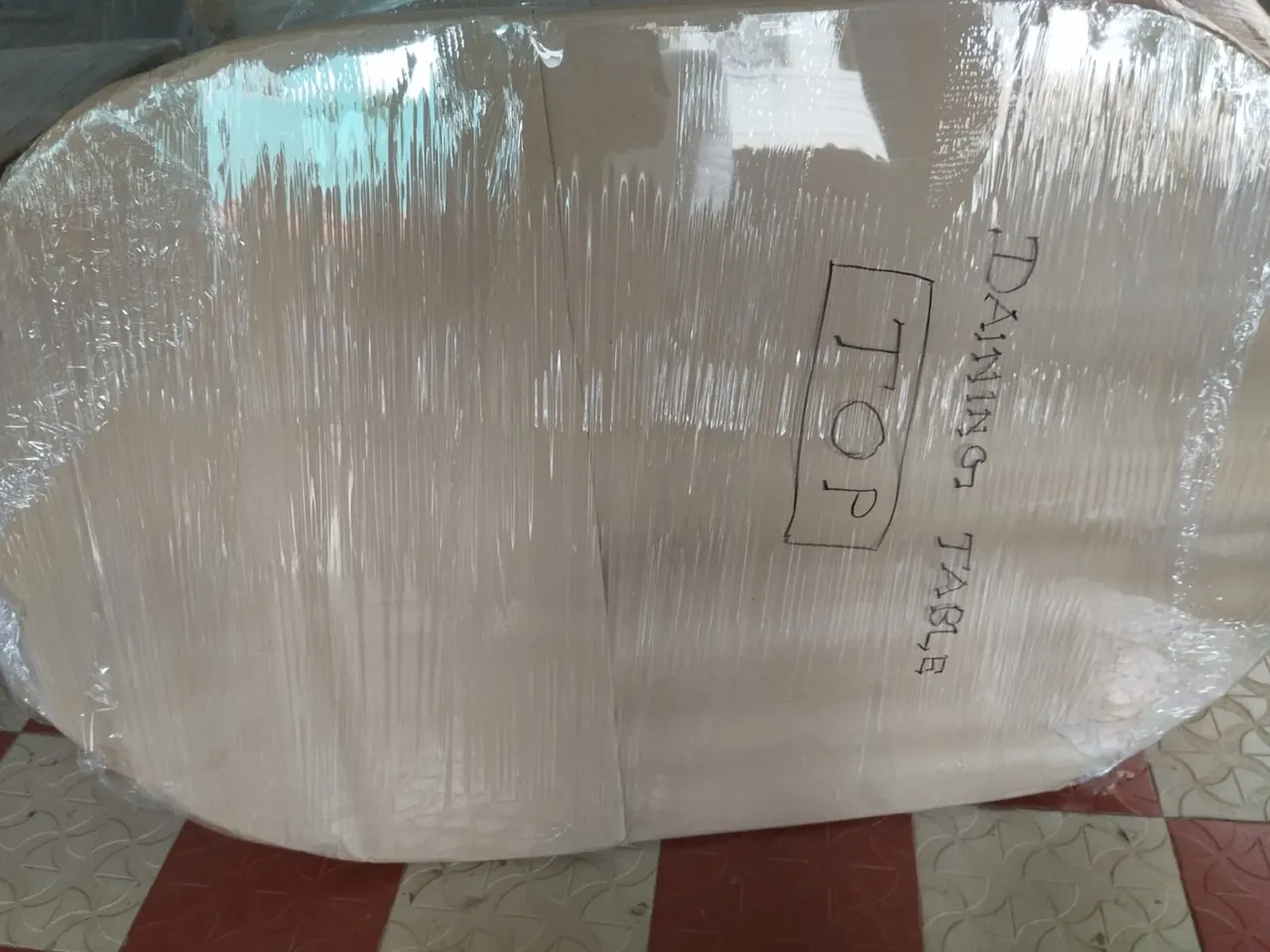 Dining table top packed in cardboard, marked TOP and labelled for moving